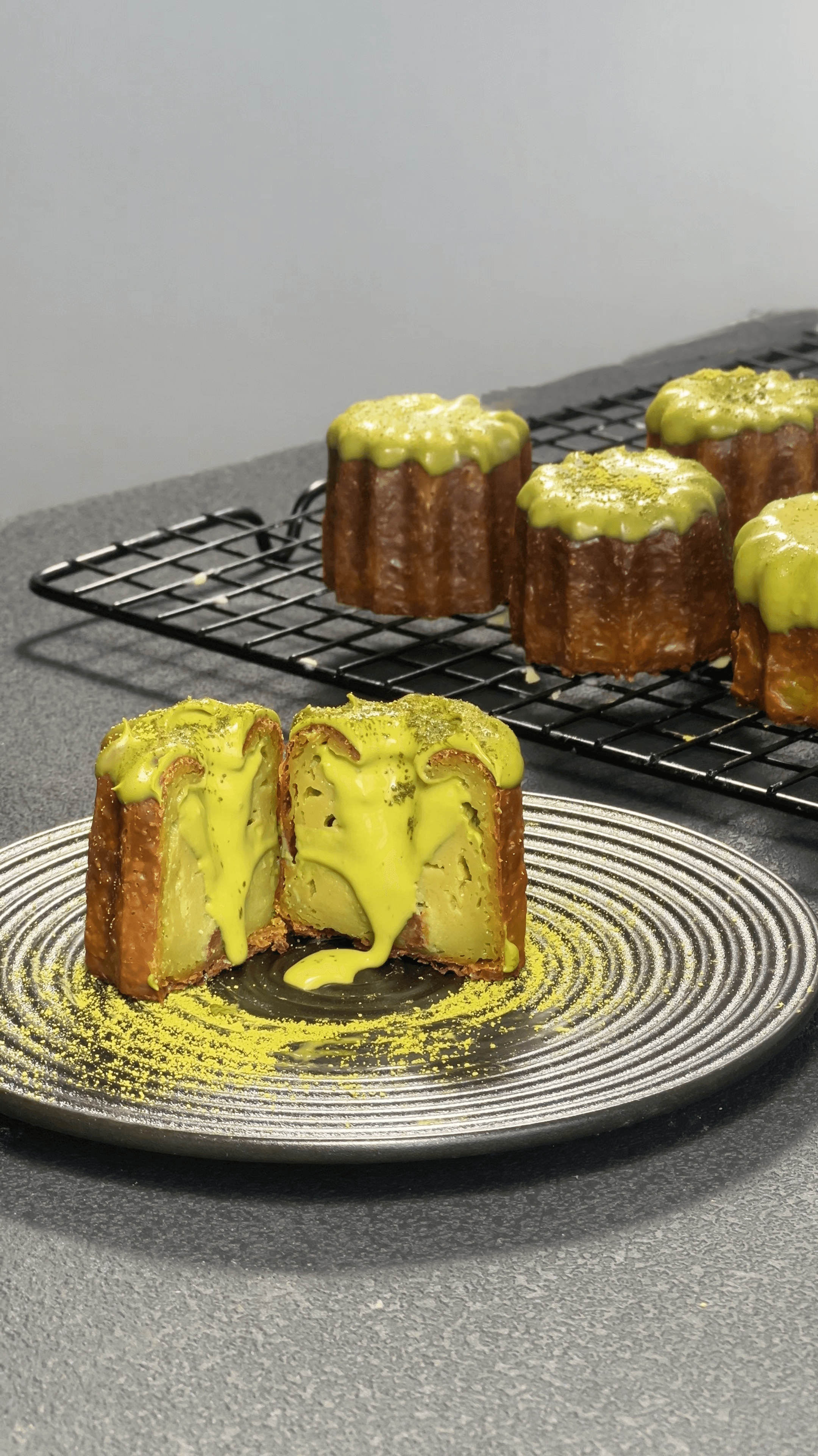 A Matcha Lava canelé split open, its molten ceremonial-grade Uji matcha core pouring onto a dark slate plate